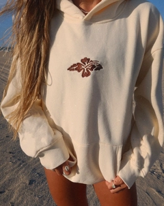 Close-up of brown hibiscus flower embroidery on cream-colored oversized drawstring hoodie