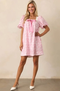 Detail of floral mini dress with square neckline, lace trim, and pink satin bow