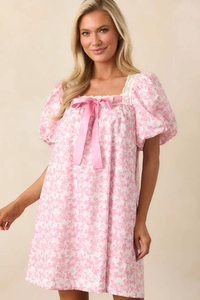 Close-up of square neckline with lace trim and large pink silk bow on floral dress