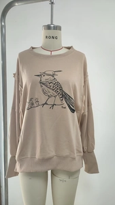 Detail of beige crewneck sweatshirt featuring artistic bird graphic and ribbed cuffs