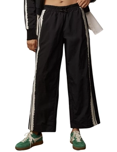Detail of black wide-leg joggers featuring white side stripes and drawstring waist
