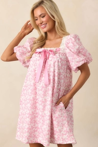 Detail of square neckline with white lace trim and pink satin bow on floral dress
