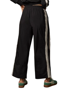 Detailed close-up of side lace trim and ruffled stripes on black wide-leg joggers