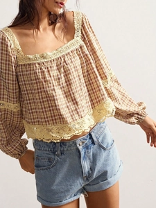 Detail of plaid blouse featuring elegant lace embroidery on the neckline and hem