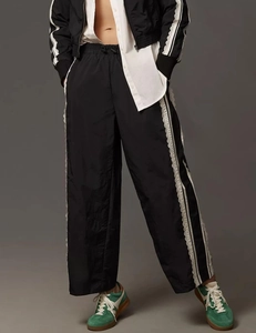 Detail of high-waist wide-leg trousers featuring white side stripes and lace trim stitching