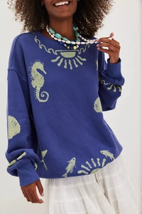 Detail of navy blue knit sweater featuring sea horse and sun prints with ribbed cuffs