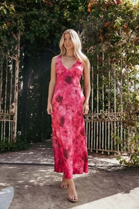 Floral pink maxi dress with deep V-neck and halter neck design in a garden setting