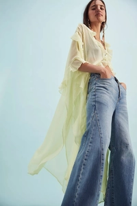 Detailed view of pale green ruffle chiffon blouse paired with wide-leg blue denim jeans