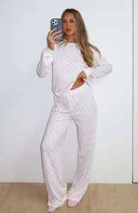 Detail of white pajama set featuring pink bow prints and ribbed collar and cuffs