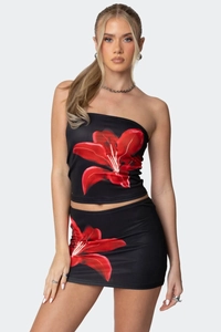 Detailaufnahme von figurbetontem Bustier und Minirock mit großen roten Lilien-Prints