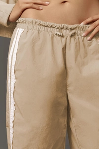 Detail of khaki wide-leg pants with elastic drawstring waist and side lace stripe decor