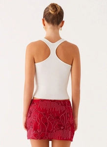 Detailansicht der roten Pailletten-Blumenstickerei und des weißen gerippten Tanktops