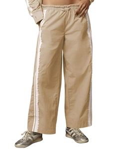 Detailed view of beige wide-leg trousers featuring white lace trim and side stripes