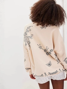 Beige oversized sweater featuring black floral and butterfly line art on the back
