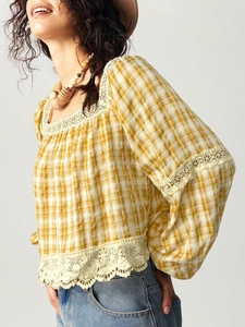 Detail of checkered blouse with white lace trim and puffy lantern sleeve style