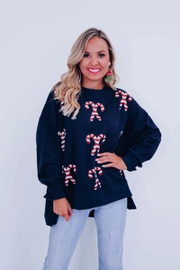 Close-up of sparkling sequined candy cane patterns on a cozy navy Christmas sweatshirt