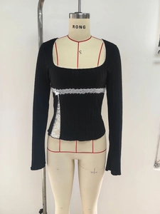 Detail of square neckline with white lace trim and bow on a black long-sleeved T-shirt