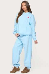 Detail of light blue fleece tracksuit featuring red heart embroidery on hoodie and joggers