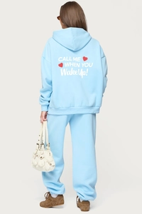 Sky blue tracksuit back view featuring white artistic font and red heart detail