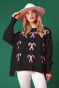 Close-up of black Christmas sweatshirt with candy cane sequins and side slit detail