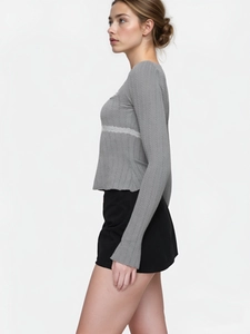 Close-up of grey cable-knit fabric featuring intricate white lace trim detailing