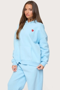 Detail of light blue hoodie and joggers set featuring a red heart logo and kangaroo pocket