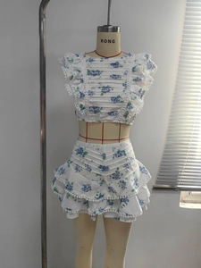 Detail of blue floral print on white cotton set with ruffle sleeves and scallop trim