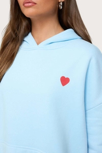 Detail of light blue hoodie featuring a small red heart print on the left chest