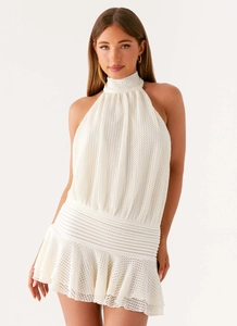 Detail of white knit halter neck mini dress featuring elastic waist and ruffle hemline