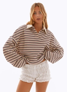 Dettaglio di maglia polo a righe oversize con colletto bianco e pantaloncini a balze