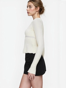 Detail of white long sleeve knit top with flared cuffs and waffle texture for women