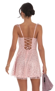 Detailweergave van de roze pailletten mini-jurk met een rugloos vetersysteem en bandjes
