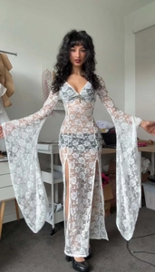 Detail of white floral lace dress with deep V-neck, flared sleeves and high side slit