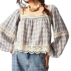 Detail of blue plaid fabric with white floral lace trim on a bohemian style blouse