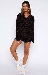 Detail of soft black pajama set featuring red lip prints and button-down long sleeves