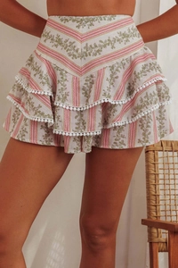 Detail of bohemian tiered skirt with floral print and white pom-pom trim accents