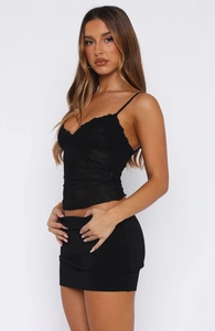Détail du caraco noir à col en V avec dentelle florale délicate et tissu en maille transparente