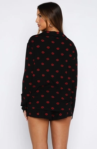 Rear view of black long-sleeve pajama set featuring vibrant red lip print patterns