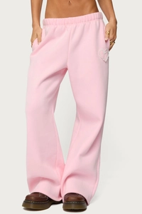 Detail of pink fleece wide-leg sweatpants featuring a white lace heart and elastic waist