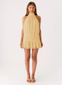 Detail of light yellow halter mini dress featuring vertical pleats and layered ruffle hem