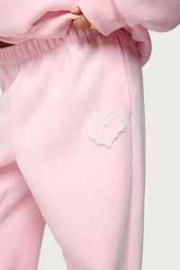 Detail of pink sweatpants with white lace heart patch and soft fleece fabric texture
