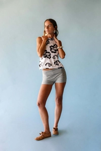 Detailed view of women's halter neck top with black leaf print and asymmetrical hemline