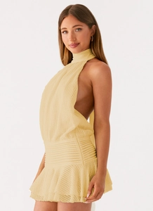 Detailed close-up of light yellow crochet knit texture on a backless halter mini dress