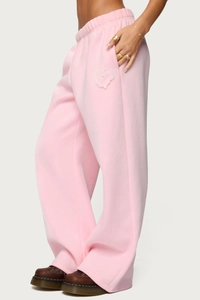 Detail of pink high-waisted sweatpants with elastic waistband and white lace heart embroidery