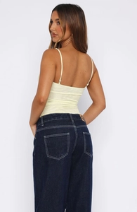 Détail du caraco côtelé jaune clair et du jean bleu à taille haute avec coutures blanches