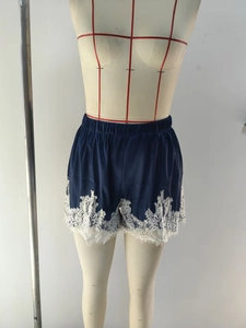 Détail de short en satin bleu marine avec large bordure en dentelle blanche fleurie