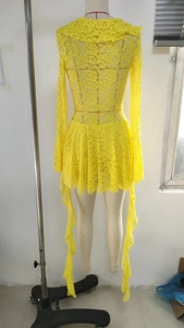 Detail of yellow floral lace fabric with ruffled neckline and long ribbon ties