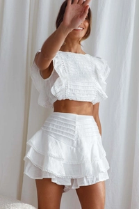 Detail of white two-piece summer set with delicate lace trim and ruffled mini skirt