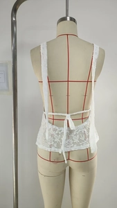 Dettaglio di un top in pizzo bianco con schiena scoperta e lacci regolabili