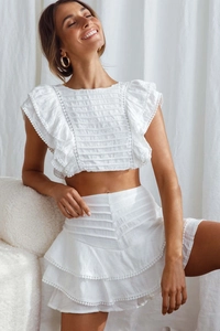 Detail of ruffled white crop top with lace trim and layered bohemian skirt